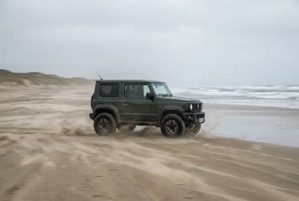 Suzuki Jimny driving through soft beach sand