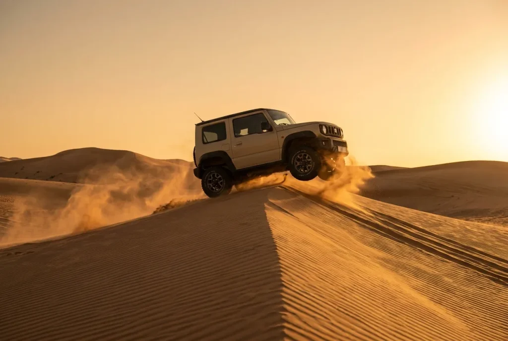Suzuki Jimny cresting a soft dune with momentum