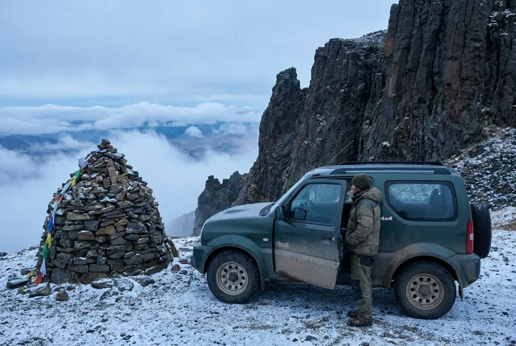 Suzuki Jimny at the summit beside a stone cairn